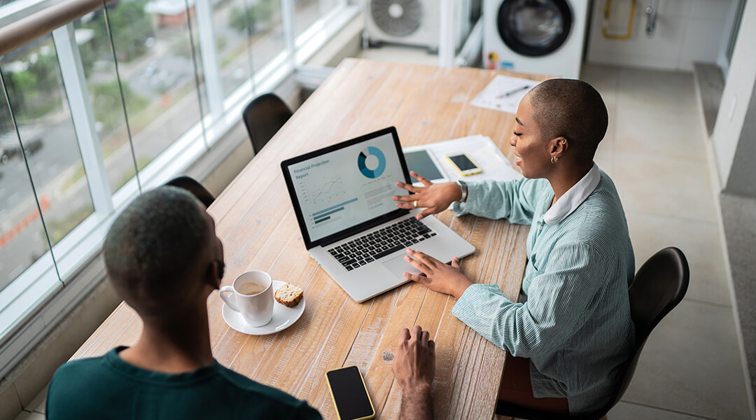 Two people reviewing loan options on a laptop at a table.